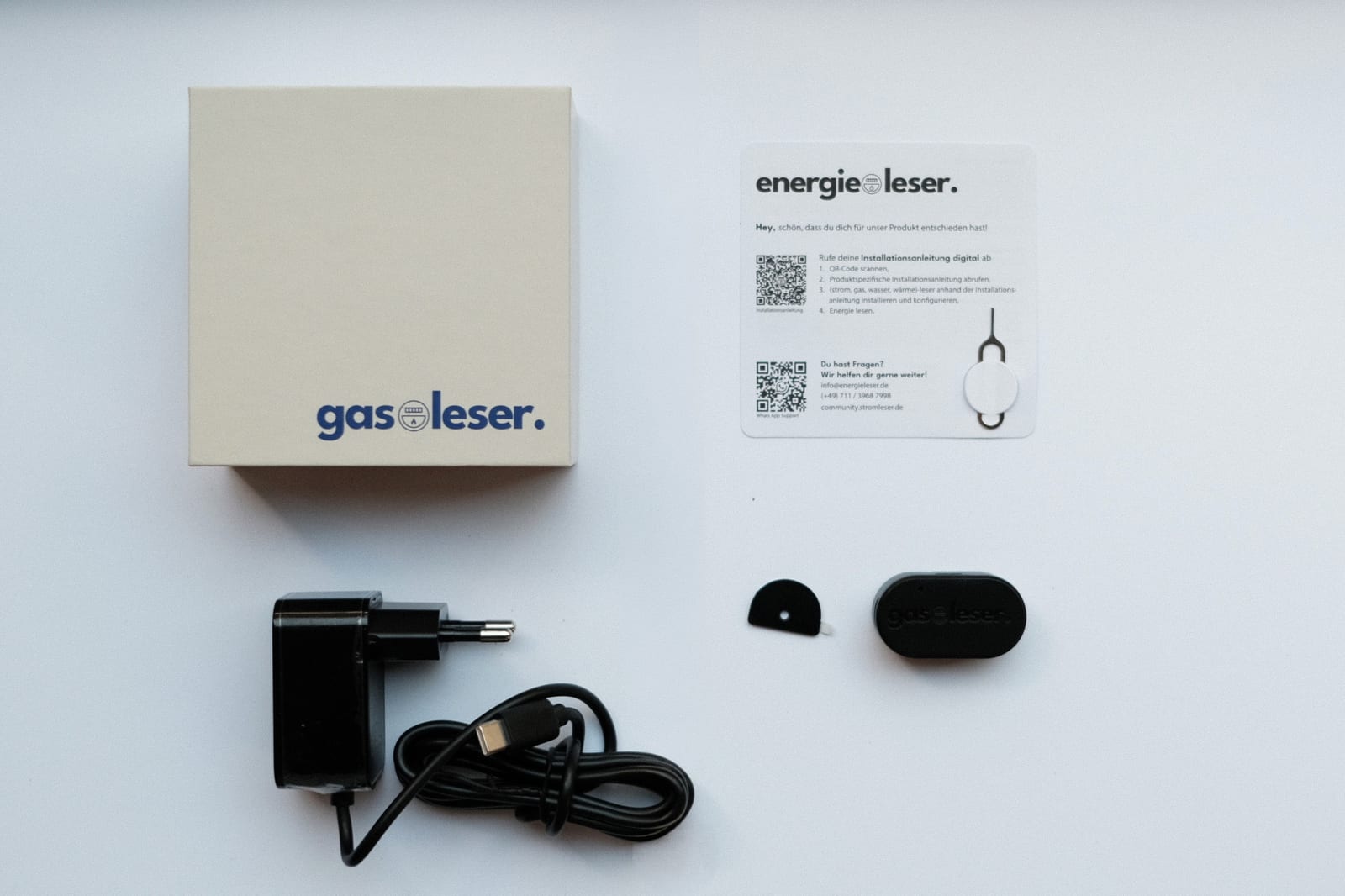 Lieferumfang des gasleser.pulse: Verpackung, Installationskarte, Netzteil mit USB-C-Kabel, Metallplatte und das Gerät